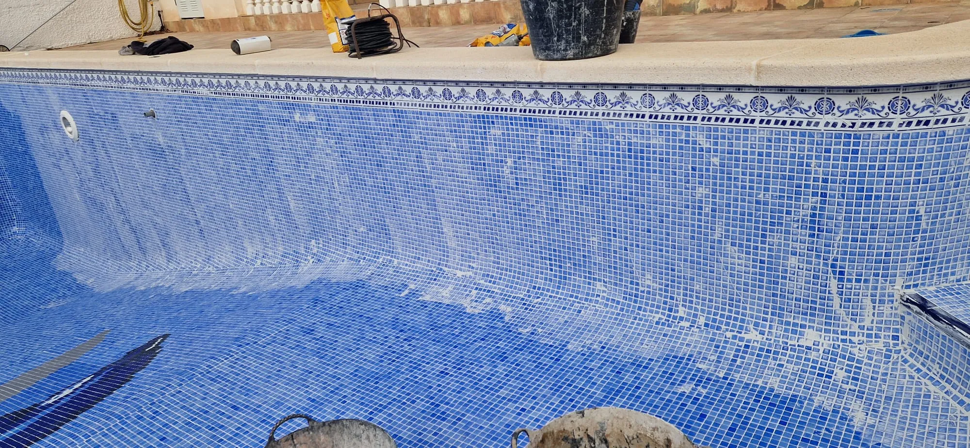 Vaso vacío durante una rehabilitación, con restos de lechada en las paredes y herramientas en el borde