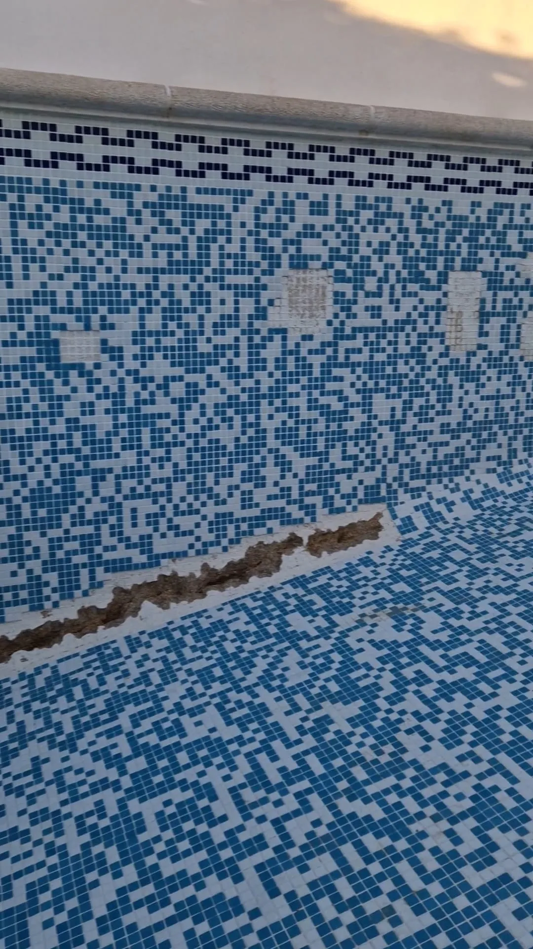 Pared de gresite abierta en una franja para llegar a la tubería con fuga